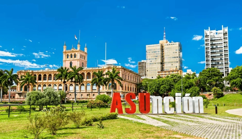 Asunción sign with the Palacio de los López, palm trees and city buildings in Paraguay